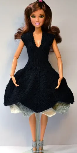 Barbie i svart stickad klänning med vit och grå volang.