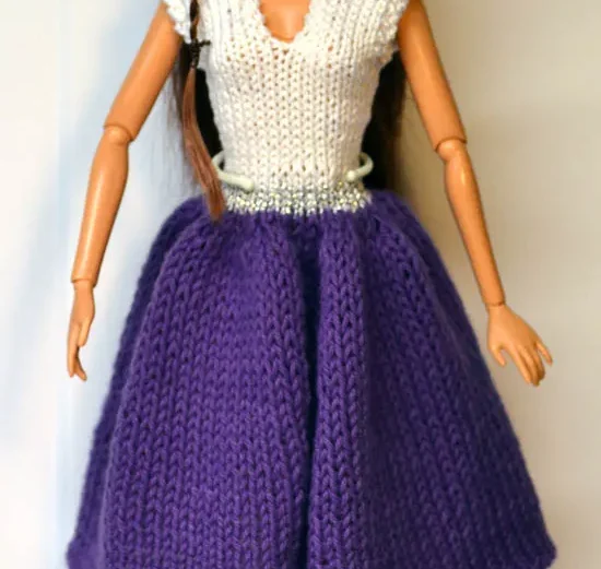 Barbie i stickad lila kjol och vit topp med silverband i midjan.