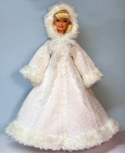 Barbie i vit stickad vinterkappa med pälsluva och pälskanter.