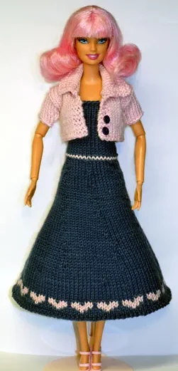 Barbie i stickad blå klänning med rosa jacka och mönstrad kant.