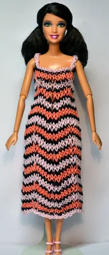 Barbie i stickad klänning med rosa, orange och svart sicksackmönster.