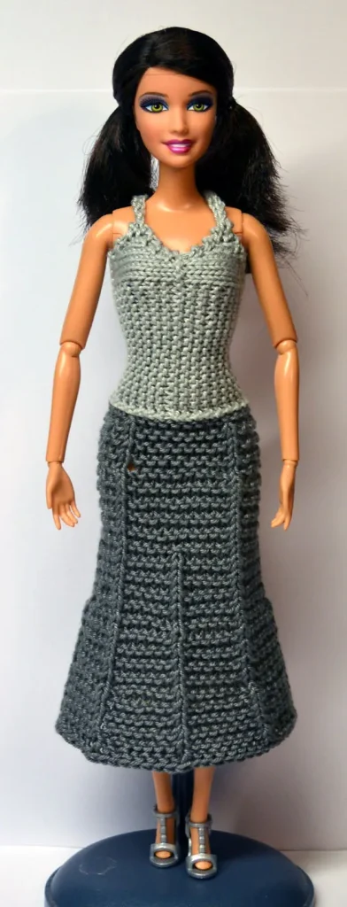 Barbie i stickad grå klänning med ljusgrå linne och mörkgrå kjol.
