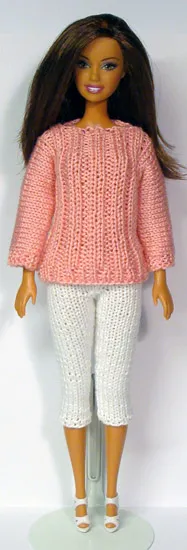 Barbie i rosa stickad tröja och vita capribyxor.