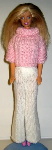 Barbie i rosa stickad tröja med polokrage och vita byxor.