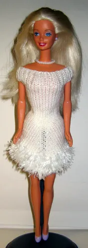Barbie i vit stickad klänning med vit pälsfrans.