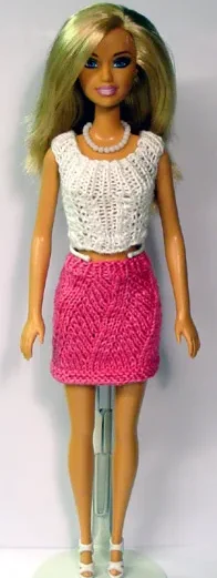Barbie i cerise rosa kjol med hålmönster och vit stickad topp.