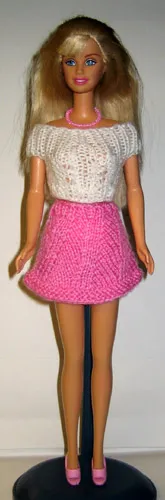 Barbie i rosa stickad kjol med hålmönster och vit topp.