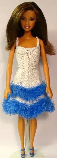 Barbie i vit stickad klänning med blå luddkant.