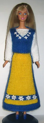 Barbie i stickad svensk folkdräkt med gul kjol, blå detaljer och vit blus.