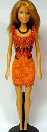 Barbie i orange stickad klänning med svarta banddetaljer framtill.