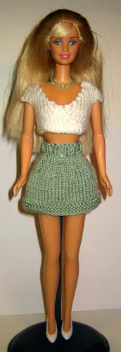 Barbie i vit stickad omlott-topp och grön kjol.