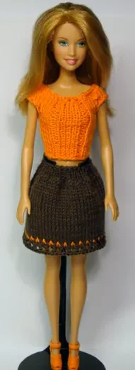 Barbie i orange stickad topp och grå kjol med orange detaljer.