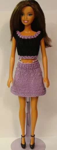 Barbie i svart stickad topp och lila kjol med resårmönster.