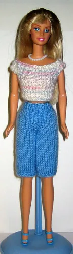Barbie i vit stickad topp och blå knäkorta byxor.