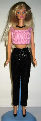 Barbie i rosa stickad topp och svarta byxor.