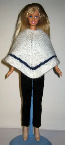Barbie i vit stickad poncho med blå rand och svarta byxor.