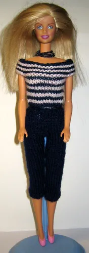 Barbie i blå och rosa randig stickad topp med mörka byxor.