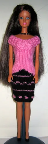 Barbie i rosa stickad klänning med svarta ränder och mönster.
