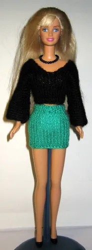 Barbie i svart V-tröja med vida ärmar och grön minikjol.
