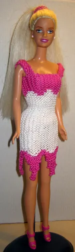 Barbie i stickad cerise och vit klänning med asymmetrisk kant.