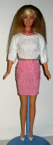 Barbie i vit stickad topp och rosa kjol.