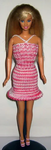 Barbie i rosamelerad stickad bandeau-klänning med vita pärlor.