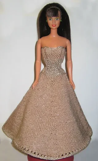 Barbie i beige stickad balklänning med gulddetaljer och hålmönster.