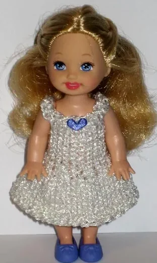 Barbie i vit glittrig klänning med blå detalj på bröstet.