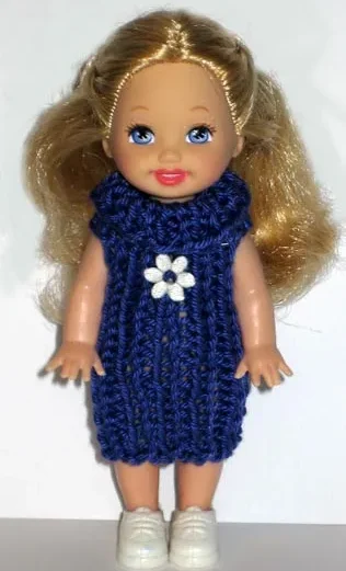 Barbie i lila stickad klänning med krage och vit blomdetalj.