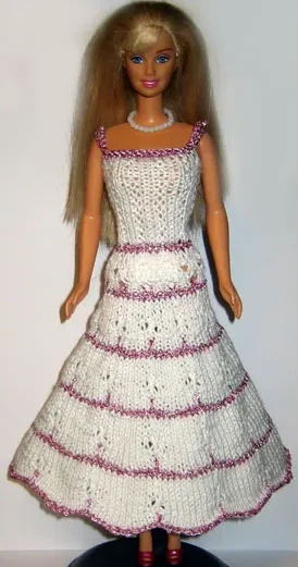 Barbie i vit stickad klänning med rosa ränder och hålmönster.