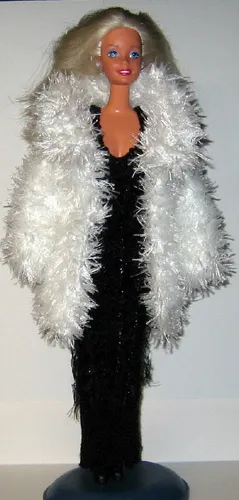 Barbie i vit pälsjacka med stor fluffig krage över svart klänning.