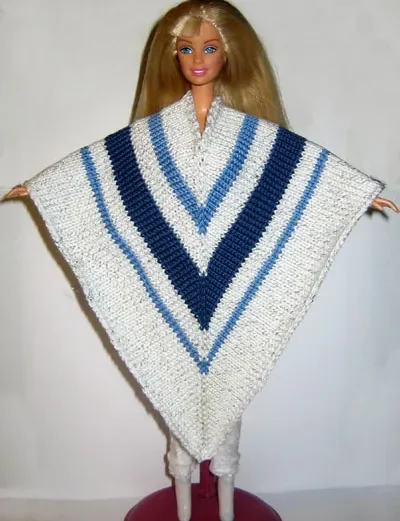 Barbie i vit stickad cape med blå ränder.