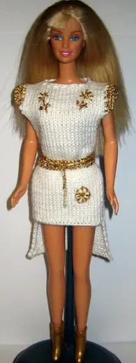 Barbie i vit stickad tunika med guldbälte och gulddetaljer.