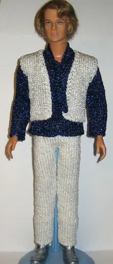Ken-docka i vit stickad väst, blå glittrig skjorta och vita byxor.