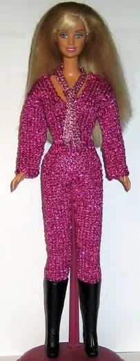 Barbie i lila glittrig jumpsuit med djup v-ringning och svarta stövlar.