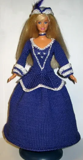 Barbie i lila stickad klänning med vita spetsdetaljer och diadem.