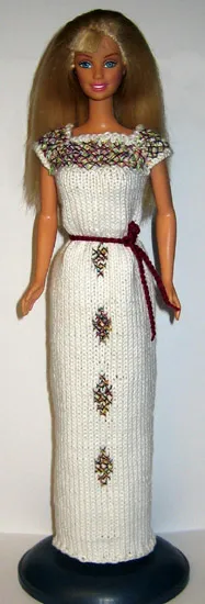 Barbie i vit stickad lång klänning med blommönster och vinrött bälte.