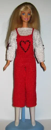 Barbie i röda stickade hängselbyxor med hjärtbroderi och vit långärmad blus.