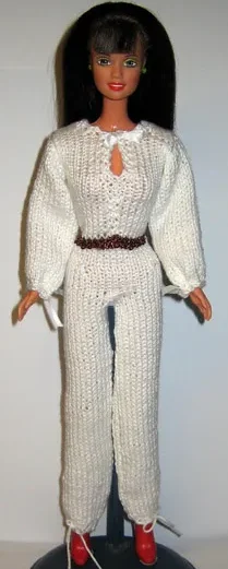 Barbie i vit stickad jumpsuit med v-ringning och mörkt skärp.
