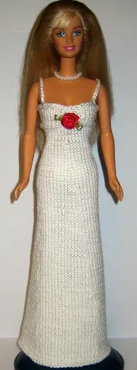 Barbie i vit lång stickad klänning med röd rosettdetalj.