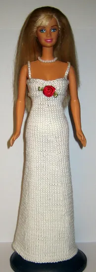 Barbie i vit lång stickad klänning med röd rosettdetalj.