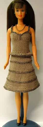 Barbie i brun stickad klänning med glitterränder.