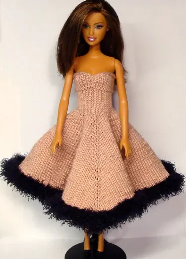 Barbie i rosa stickad klänning med svart luddkant.