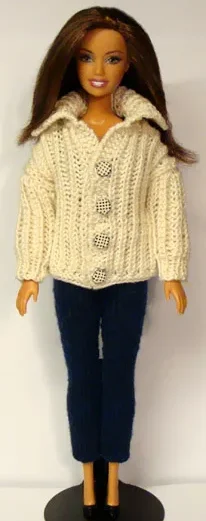 Barbie i vintervit stickad kofta med knappar och svarta byxor.