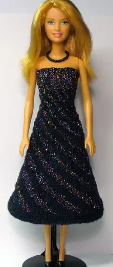 Barbie i svart klänning med glitterränder i diagonalt mönster.