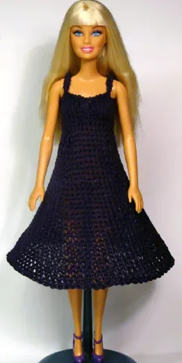 Barbie i mörklila stickad klänning med hålmönster och axelband.