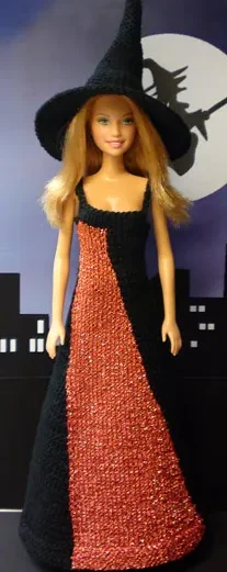 Barbie i orange och svart stickad lång klänning med svart häxhatt.