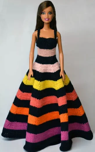 Barbie i randig stickad långklänning med svarta avdelningar och färgglada band.