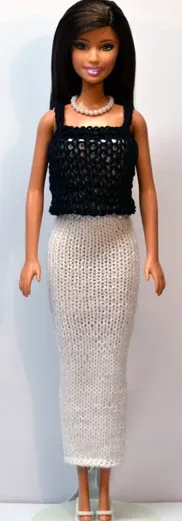 Barbie i vit långklänning med svart bandeau-topp och pärlhalsband.