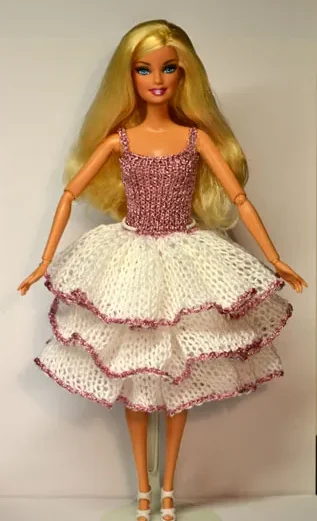 Barbie i vit stickad klänning med rosa glittrig topp och volangkjol.